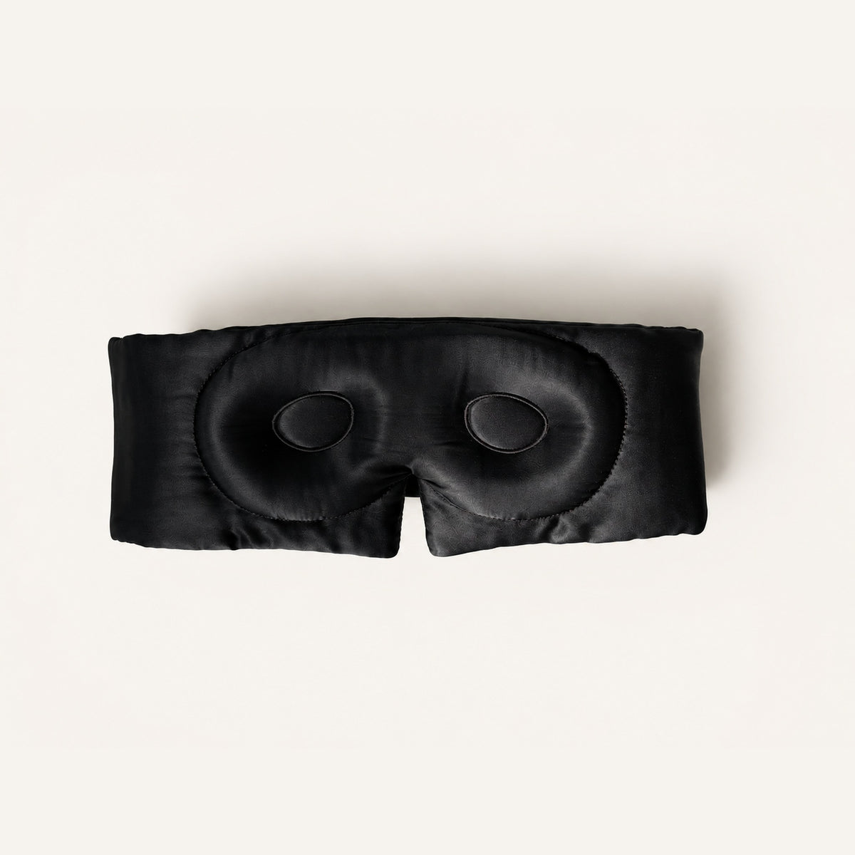 Gora Silk Sleep Mask in Umbra seen from the inside — a black 3D contoured mulberry silk sleep mask with moulded eye cups on a cream background